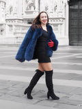 Chic blue fox fur coat draped over shoulders, revealing a black mini dress. A stylish and elegant winter fashion piece.