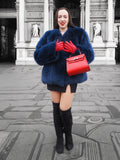 Plush blue fox fur jacket styled with a red handbag and gloves. A luxurious and warm outerwear choice for winter elegance.