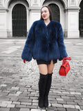 Stylish blue fox fur jacket with a rich texture, paired with a red handbag. A luxurious winter coat for fashion-forward individuals.