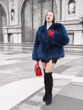 Elegant blue fox fur jacket with a soft crew neck, styled with a red handbag. A sophisticated winter coat for a bold fashion statement.