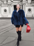 Vibrant blue fox fur jacket styled with a red handbag and black thigh-high boots. A luxurious winter coat for a bold fashion statement.