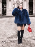 Stylish blue fox fur jacket with a rich texture, paired with a red handbag. A luxurious winter coat for fashion-forward individuals.