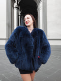 Elegant blue fox fur coat with a soft crew neck, styled with red gloves. A statement winter fashion piece for sophisticated style.