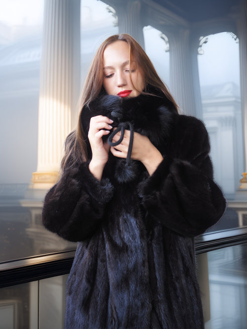 Woman wearing a black fur coat in an elegant interior setting