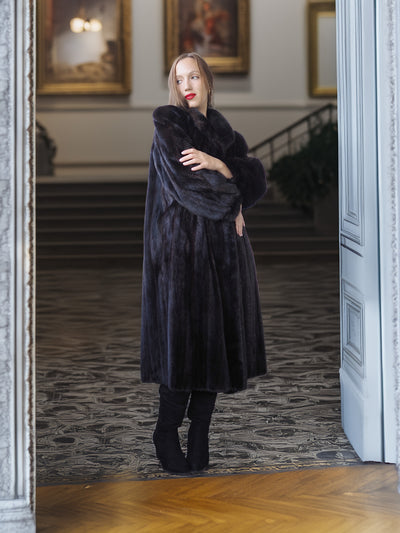 Woman wearing a long black fur coat in an elegant interior setting