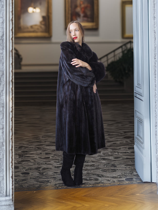Woman wearing a long black fur coat in an elegant interior setting