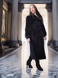 Person wearing a long black fur coat in an elegant interior setting with columns and marble floor.