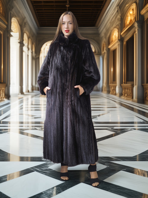 Woman wearing a long black fur coat in an elegant hallway with marble floors and high ceilings.
