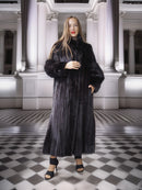 Woman wearing a long black fur coat in an elegant interior setting