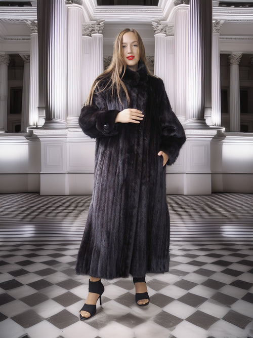 Woman wearing a long black fur coat in an elegant interior setting