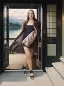 Woman in a fur coat standing in front of a door with a scenic view.