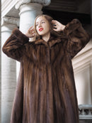Woman wearing a fur coat standing in front of classical architecture.