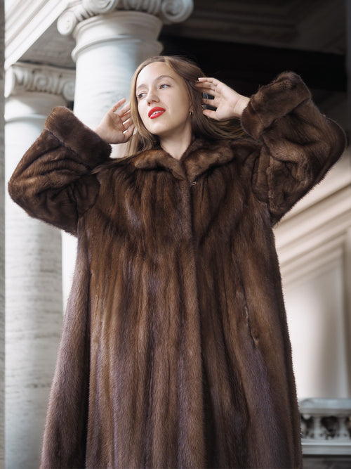 Woman wearing a fur coat standing in front of classical architecture.