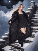 Woman in a long black coat standing on snow-covered steps with a snowy landscape and night sky in the background.