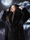 Woman in a black fur coat against a night sky with clouds and moon.