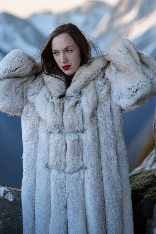 Woman wearing a fur coat with a mountainous background