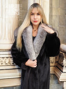 Black mink coat with light fur collar and open neckline, seated side portrait