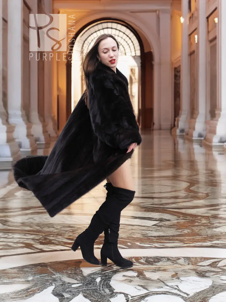 Black mink full-length fur coat with high collar and flowing hem, three-quarter side view