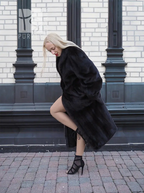 Black mink fur coat, angled side view showing long hood and voluminous sleeves.