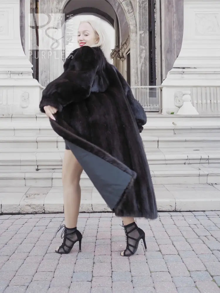 Black mink fur coat, long hooded silhouette with wide sleeves and front closure.