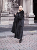 Mink fur coat in dark black with long hem and wide cuffs, side view