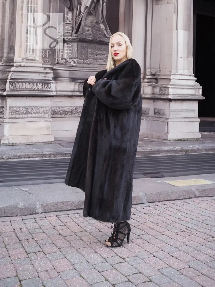 Mink fur coat in dark black with long hem and wide cuffs, side view
