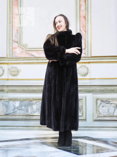 Black mink fur coat, button-front style, standing full length with arms crossed.