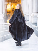 Black mink fur coat, full length silhouette, side profile with wide, flowing sleeves.