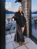 Black mink coat draped over shoulders with long flared hem, side view