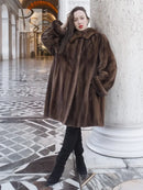 Dark brown fur swing coat with hood and voluminous sleeves, standing pose.
