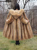 Tanuki raccoon fur coat showing back hood and flared skirt hem, tan fur, full view from behind.