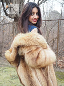 Tanuki raccoon fur coat close-up over shoulders, hood trim visible, tan plush fur texture.