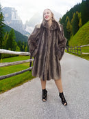 Dark fur coat with attached hood, long sleeves and flared hem in a standing view
