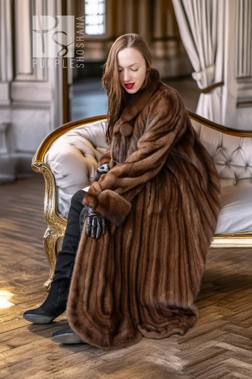Brown mink fur coat with rounded cuffs and front clasp, worn while seated