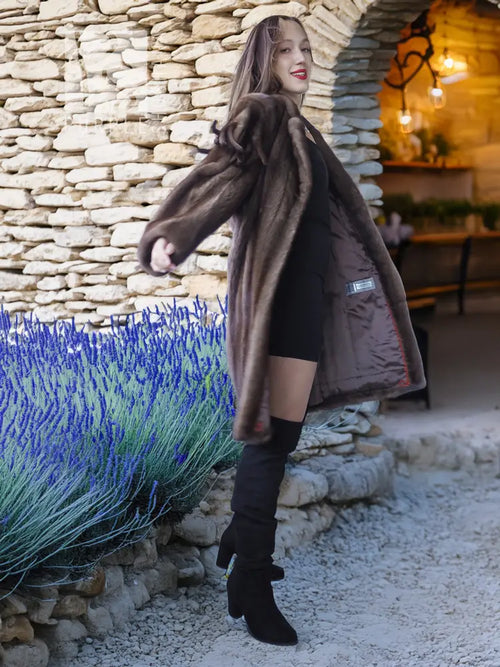 Dark brown faux mink fur coat worn over a black dress, side view