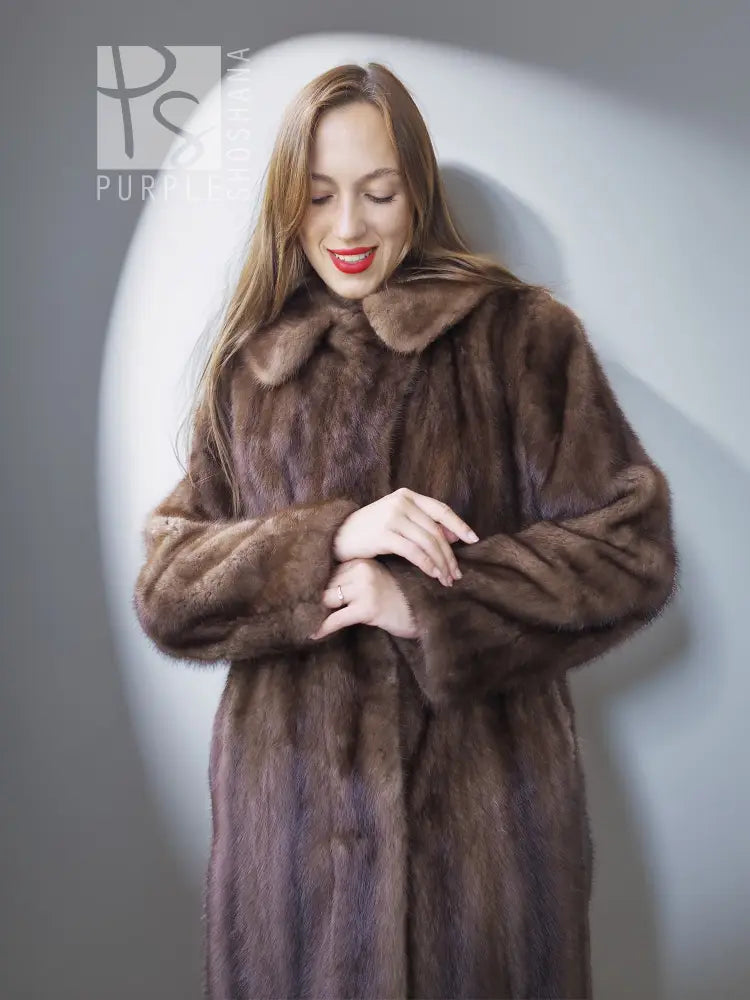 Mink fur coat close-up with stand collar and open front, brown, hands at waist