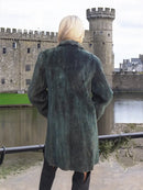 Back view of dark green sheared beaver jacket with draped hood and relaxed fit
