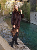 Dark mahogany-brown vintage mink fur coat, long length, standing with one hand in pocket.