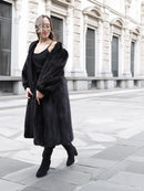 Black mink fur coat with long hem and sleeves, side view standing