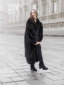 Black mink fur coat, long coat style with notched collar and draped sleeves on model.
