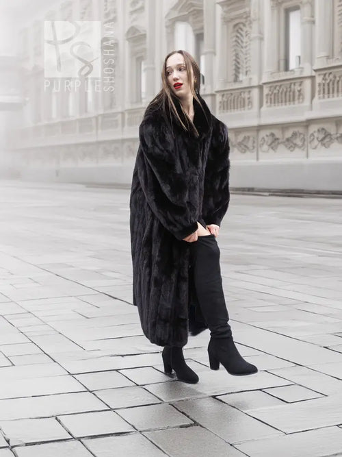 Black mink fur coat, long coat style with notched collar and draped sleeves on model.