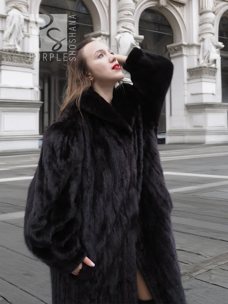 Black mink fur coat jacket with wide collar and dramatic long sleeves, side view.
