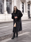Black mink fur coat with long length, notched collar, and open front worn with dark pants.