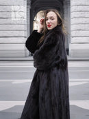 Black mink fur coat with notched collar and full sleeves, close-up at upper front and face.