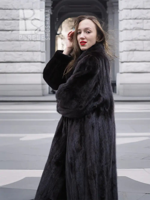 Black mink fur coat with notched collar and full sleeves, close-up at upper front and face.
