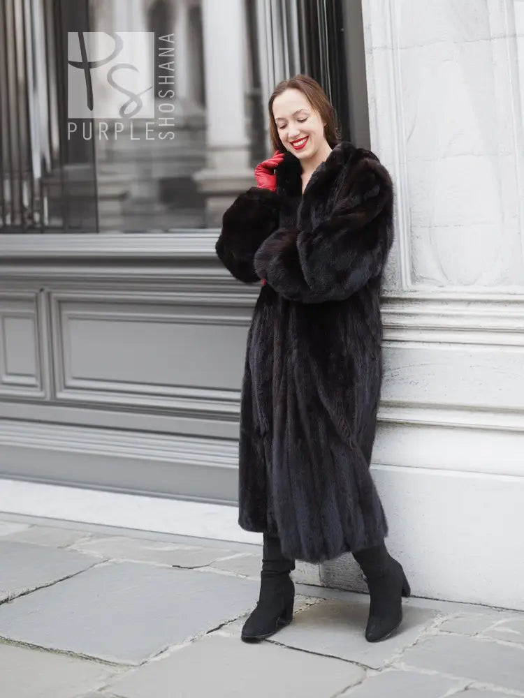 Black mink fur coat with open front and large collar, standing side view, red gloves