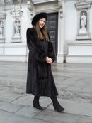 Black mink fur coat with long sleeves and matching black fur hat, standing full length