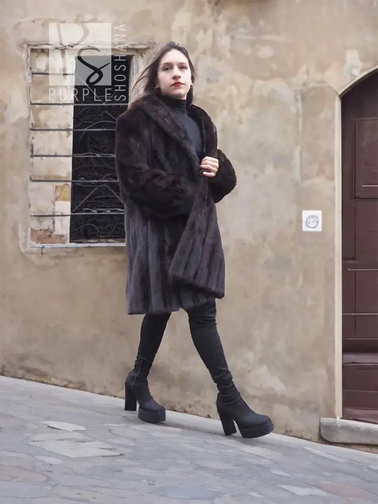 Dark hooded mink fur jacket coat, front 3/4 view, long silhouette and cuffs.