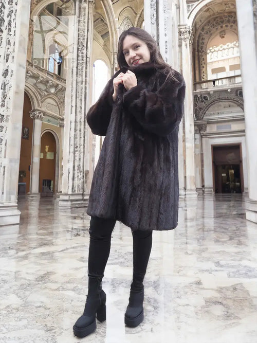 Black mink fur jacket with plush fur and long sleeves, front view in an indoor hall.