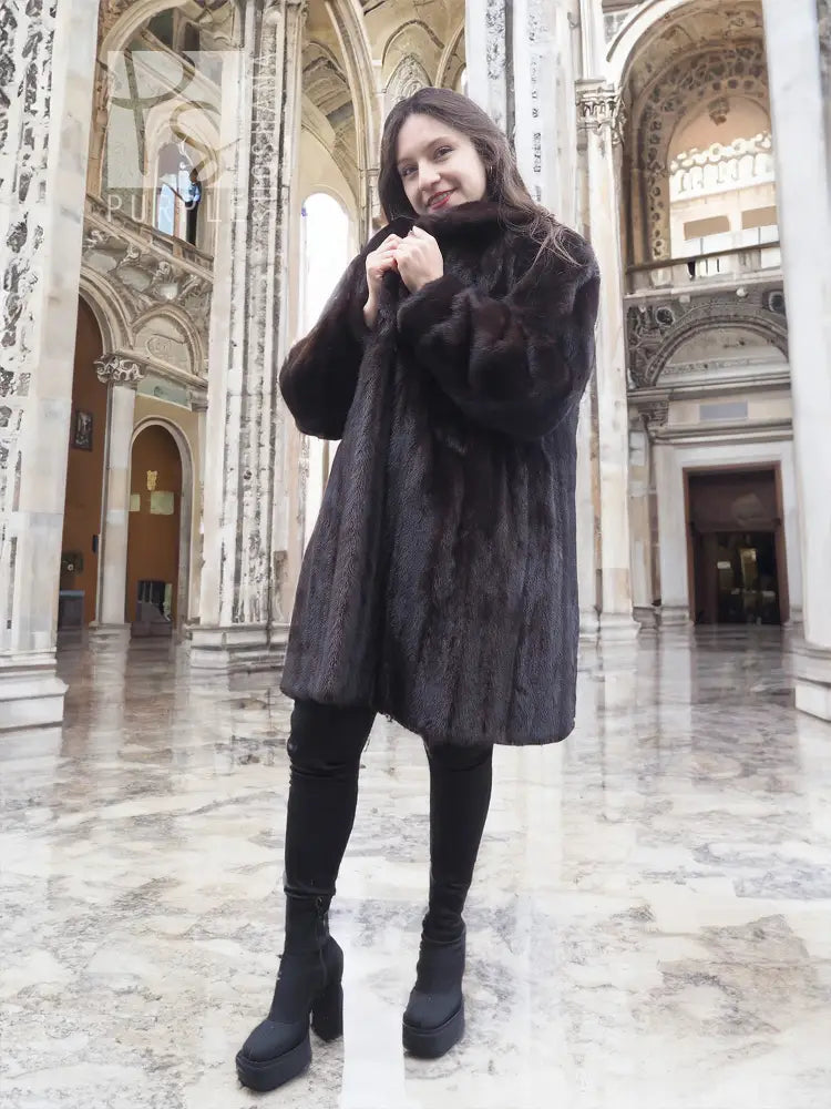 Black mink fur jacket with plush fur and long sleeves, front view in an indoor hall.